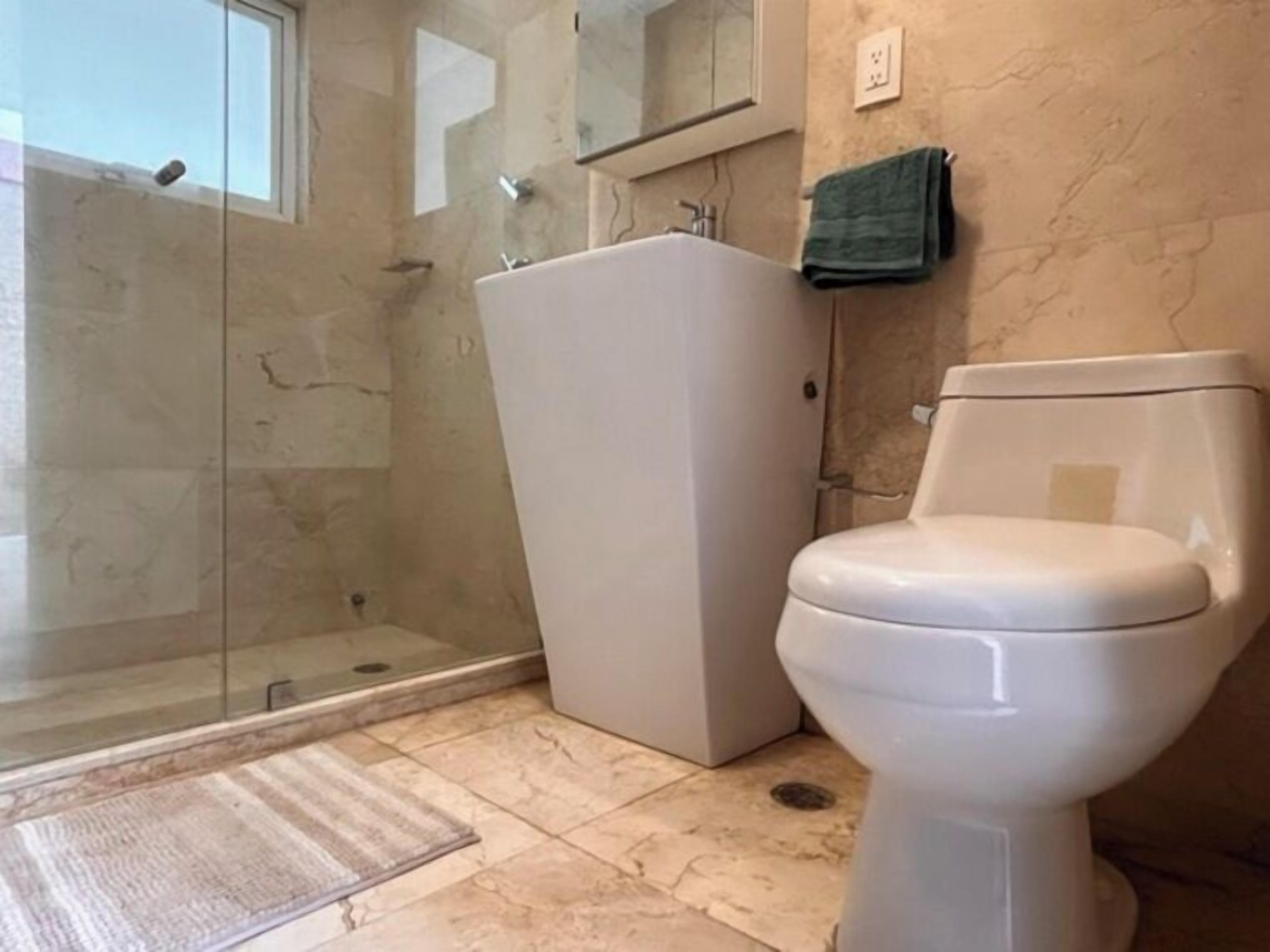 A bathroom with a toilet, a shower area, and a sink.