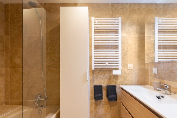 A modern bathroom with a glass shower enclosure, a white vanity with a sink, and a towel rack.