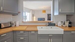 Eine moderne Küche mit grauen Schränken, einer Spüle, einer Mikrowelle und einer Kaffeemaschine.