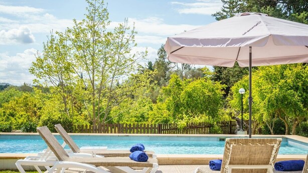 A poolside area with lounge chairs, a table, and a large umbrella.