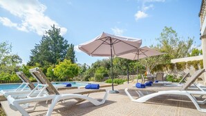 A poolside area with lounge chairs, a pool, and a pergola with a canopy.