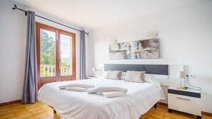 A hotel room with a large bed, a nightstand, a painting, and a balcony view.