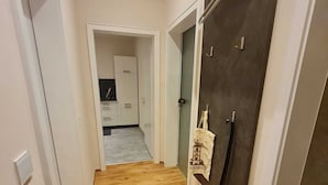 A hallway with wooden flooring leading to a kitchen area. - Charmante 2-zimmer-wohnung (Siegen)