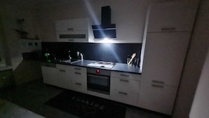 A modern kitchen with a black countertop, a built-in oven, and a microwave. - Charmante 2-zimmer-wohnung (Siegen)