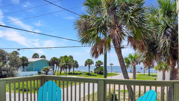 A balcony with two blue Adirondack chairs, a view of a beach, and palm trees. - Beach View Upper (Port St. Joe)