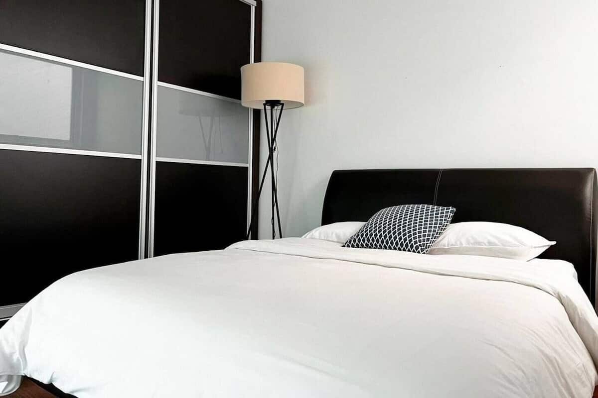 Un dormitorio con una cama, una lámpara de pie y un amplio armario negro.