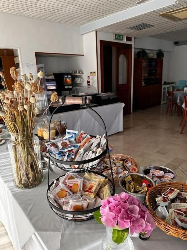 Uma mesa de buffet com diversos alimentos e um vaso de flores.