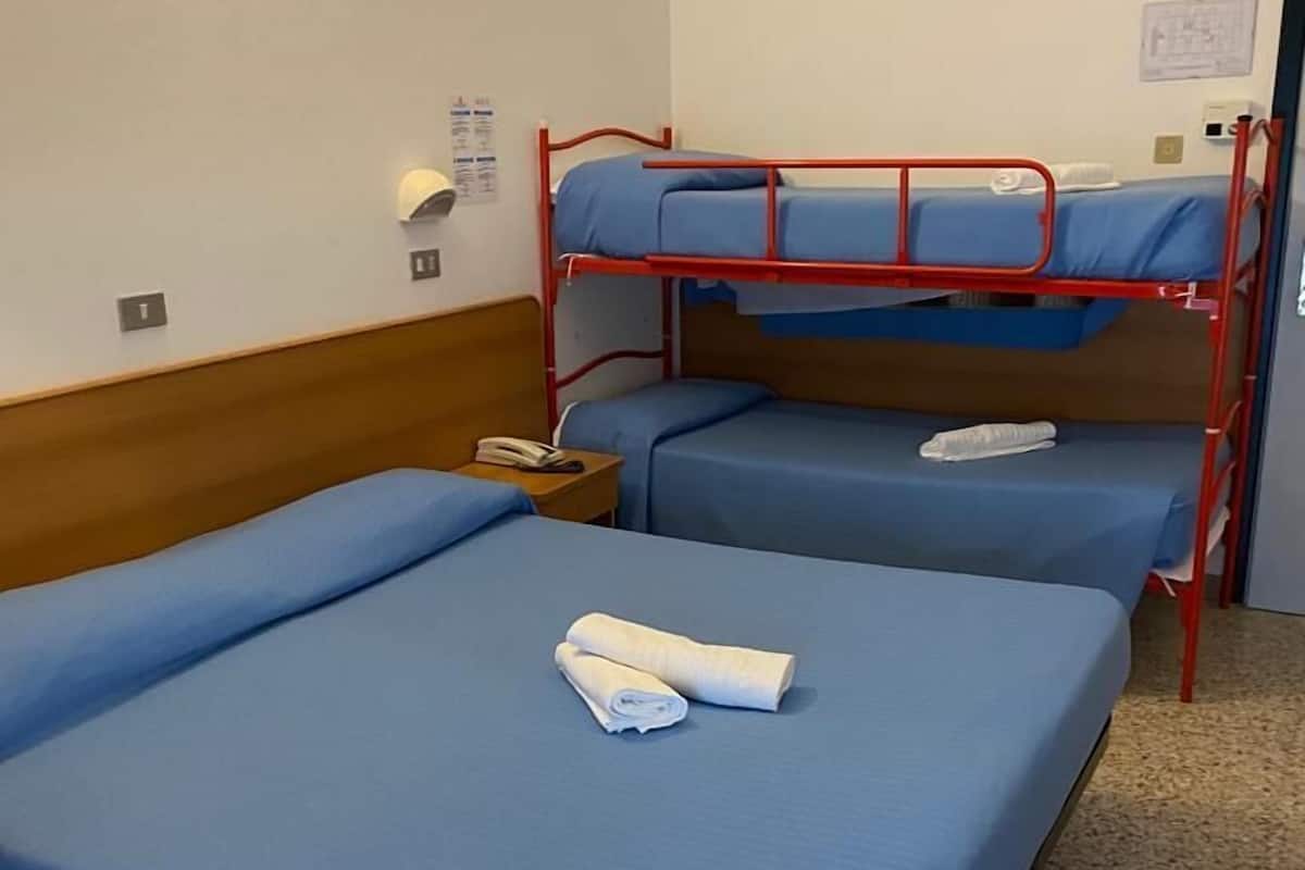 A hotel room with two single beds and a bunk bed.