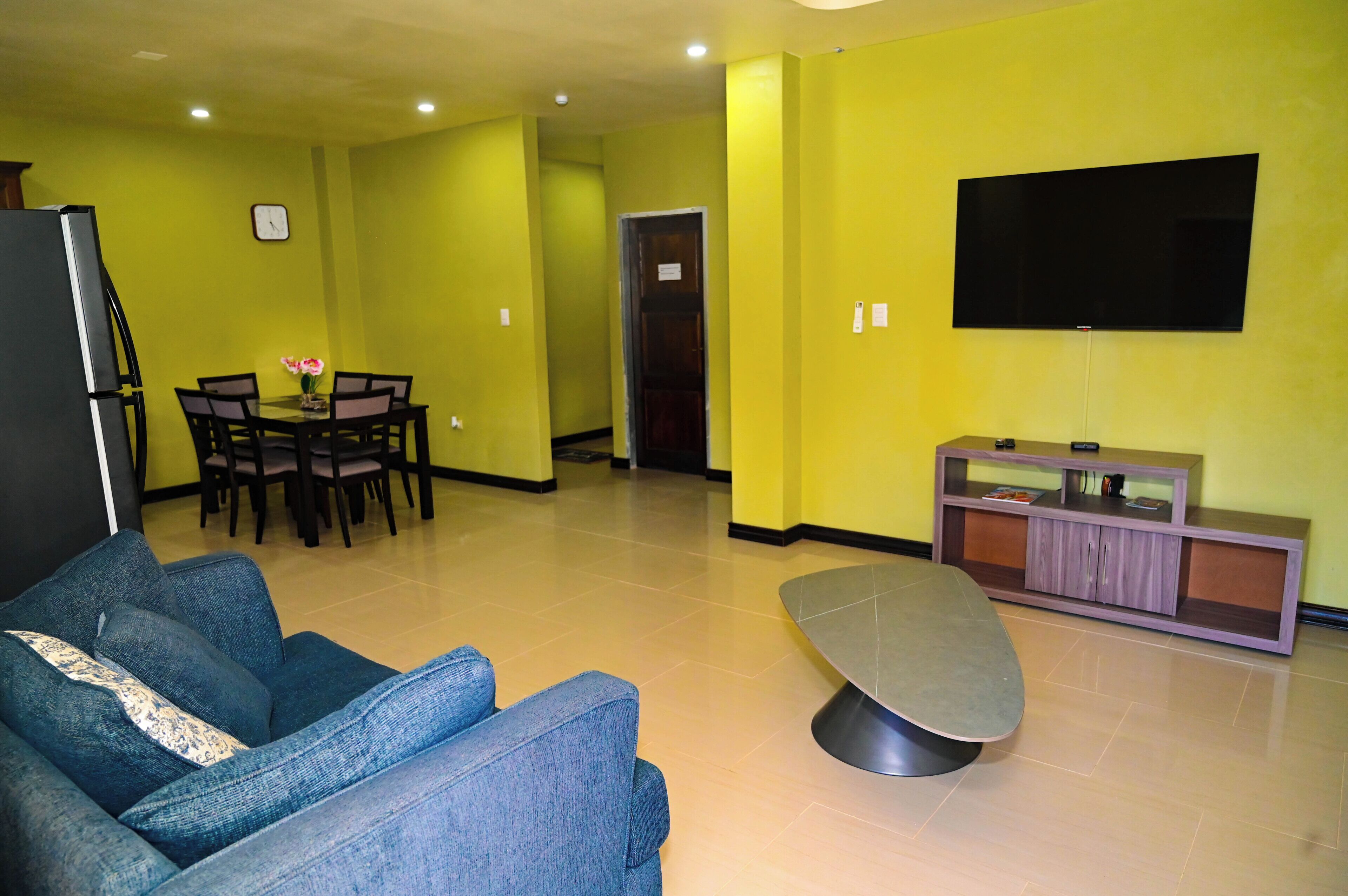 Una sala de estar con sofá, mesa de comedor con sillas, televisor y aparador.