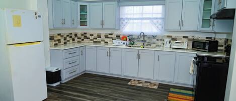 A kitchen with light blue cabinets, a white refrigerator, a microwave, and a sink.
