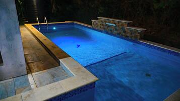 A swimming pool with a stone border and a small bar area.