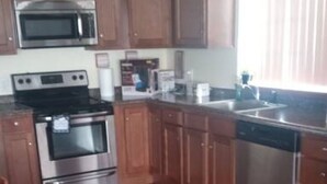 A kitchen with wooden cabinets, stainless steel appliances, and a dining area with a table and chairs.