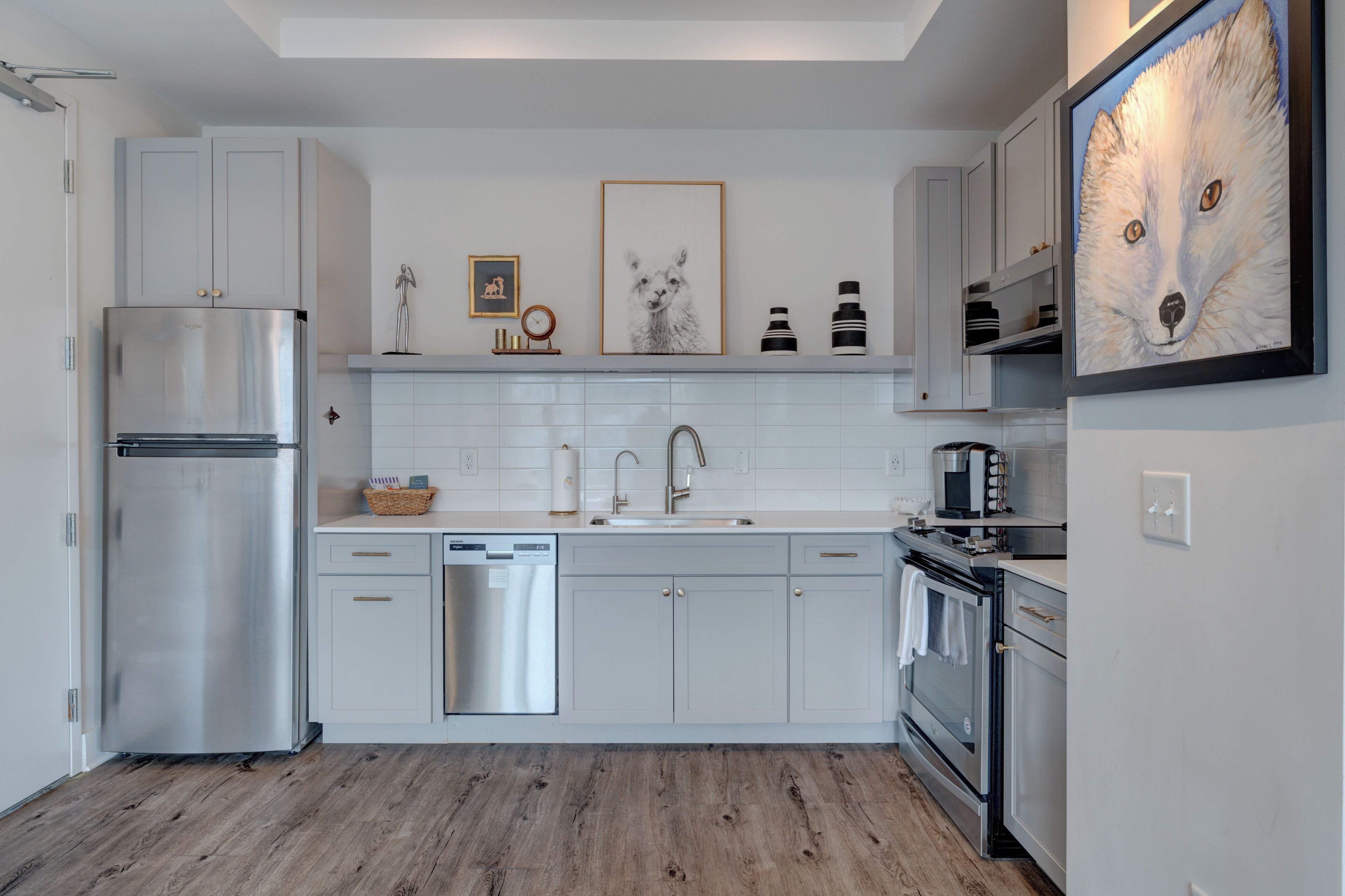 Una cocina moderna con armarios blancos, electrodomésticos de acero inoxidable y suelo de madera.