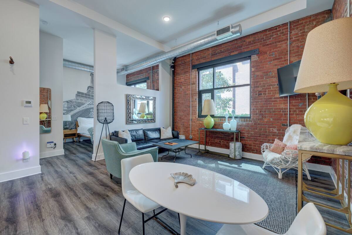 Un salon moderne avec un mur en briques, un canapé, une table basse et une table à manger.