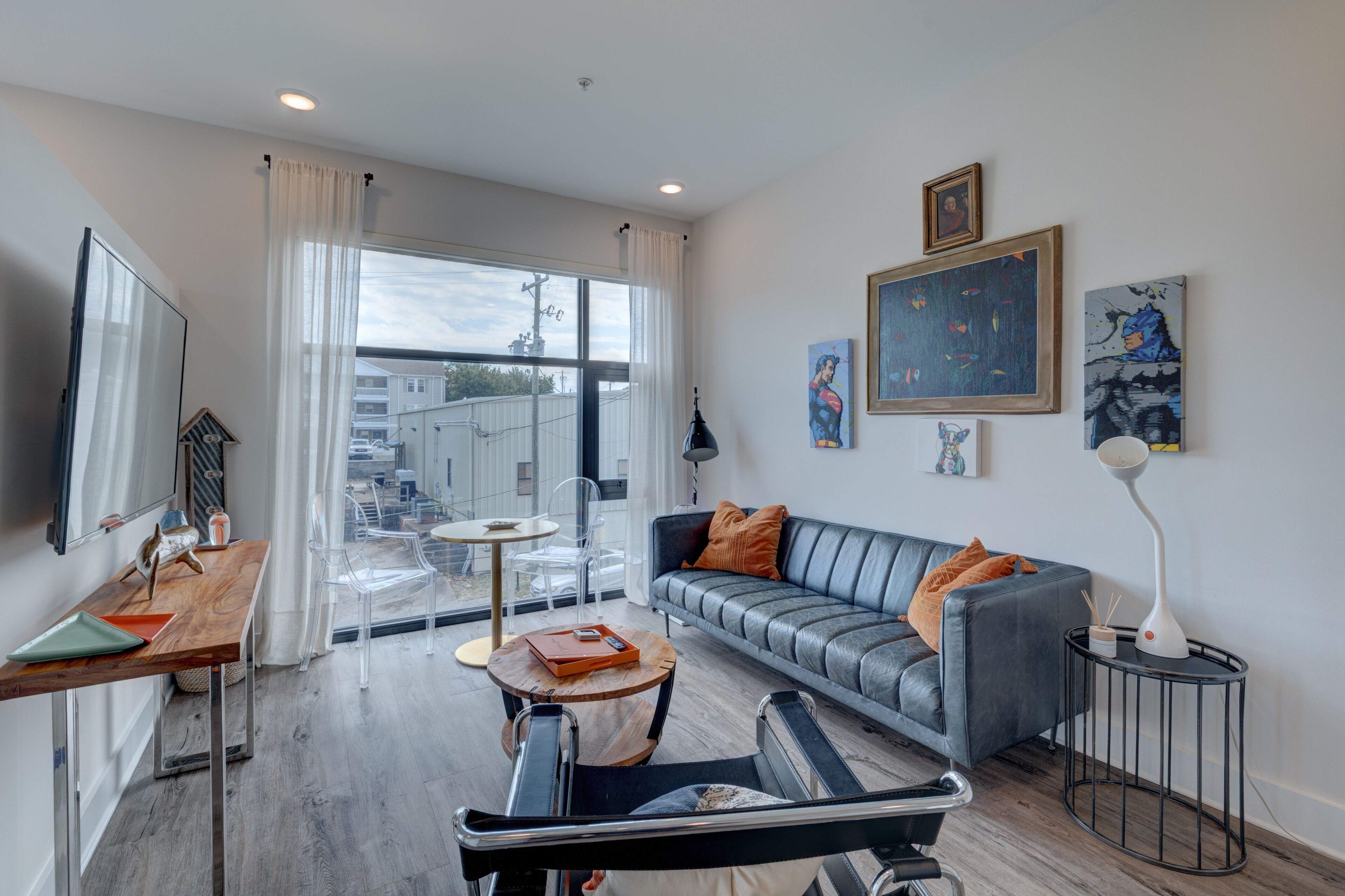 A modern living room with a grey sofa, a wooden coffee table, a TV, and artwork on the walls.