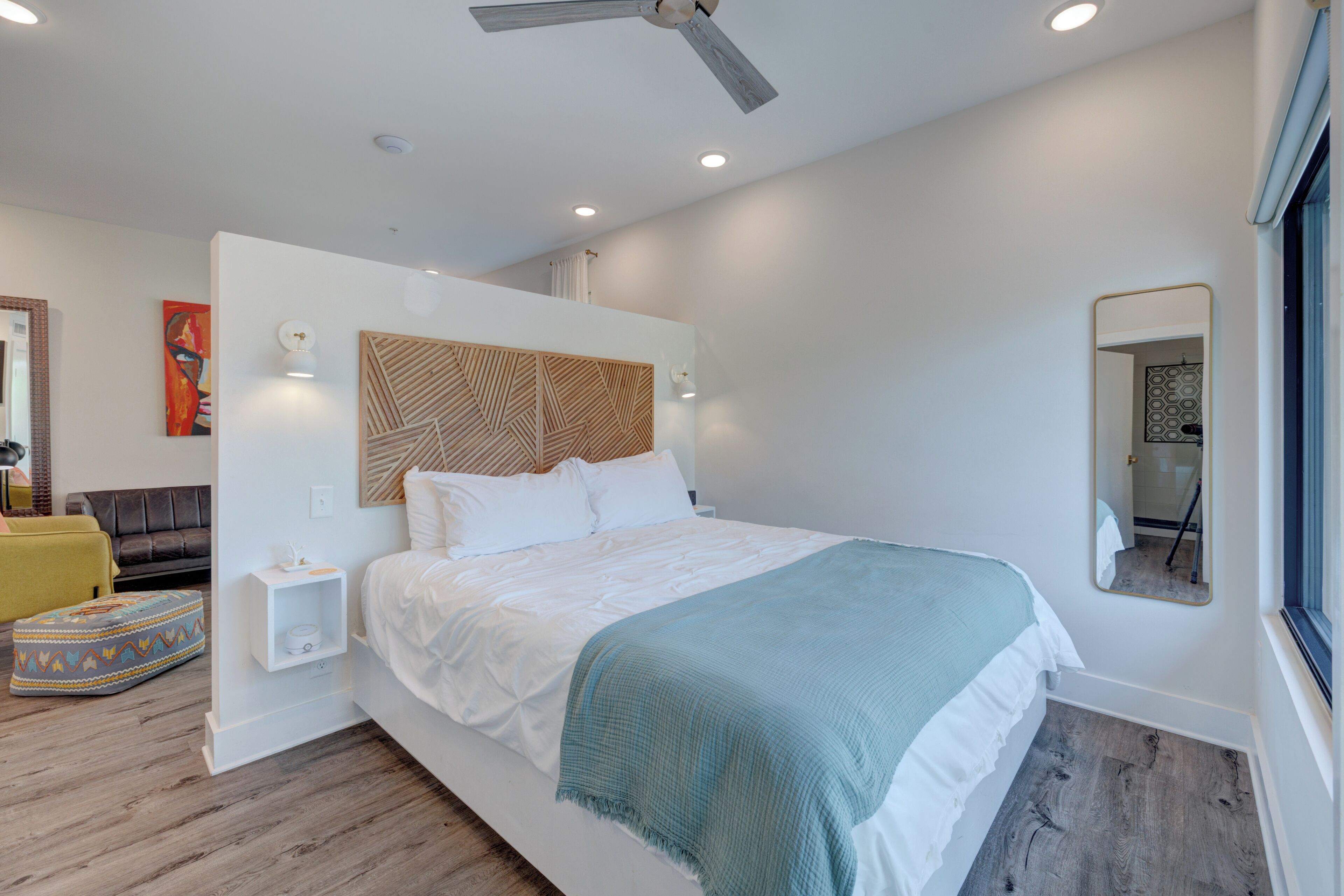 A modern bedroom with a large bed, a ceiling fan, and a bedside table with a lamp.