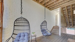 A wooden deck with two hanging chairs and a small table with plants. - The Hive (Wilmington)