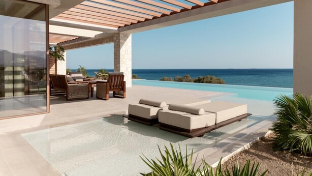 A modern outdoor lounge area with a pool, seating, and a view of the ocean. - Beachfront Brand New Villa (Ierapetra)