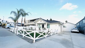 A two-story house with a white exterior, a fenced front yard, and a garage.