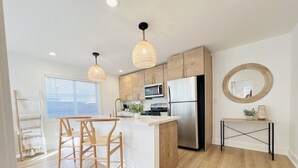 Una cocina moderna con armarios de madera, un refrigerador de acero inoxidable e una isla central con taburetes de bar.