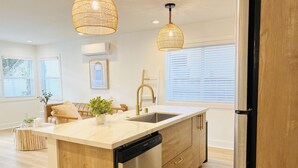 Una cocina moderna con una isla central, electrodomésticos de acero inoxidable y un armario de madera.