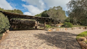A stone-paved pathway leading to a wooden pergola structure. - Villa "Olga" with Sea View, Private Terrace & Wi-Fi (Carloforte)