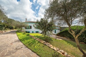 Une maison avec un chemin de pierre menant à l’entrée, entourée de verdure et d’arbres.