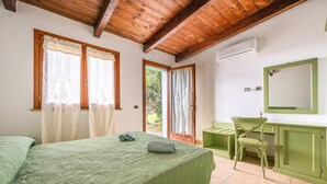 A bedroom with a bed, a desk, a chair, and an air conditioning unit. - Villa "Olga" with Sea View, Private Terrace & Wi-Fi (Carloforte)