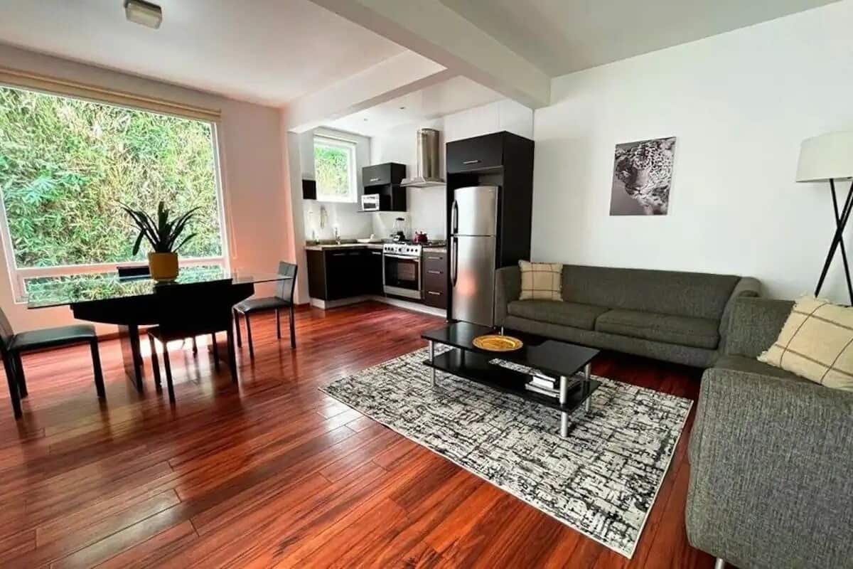 Een moderne woonkamer met een bank, salontafel en eethoek.