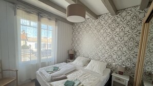 Makuuhuone, jossa on sänky, kaksi yöpöytää, ikkuna ja kuviollinen tapetti.