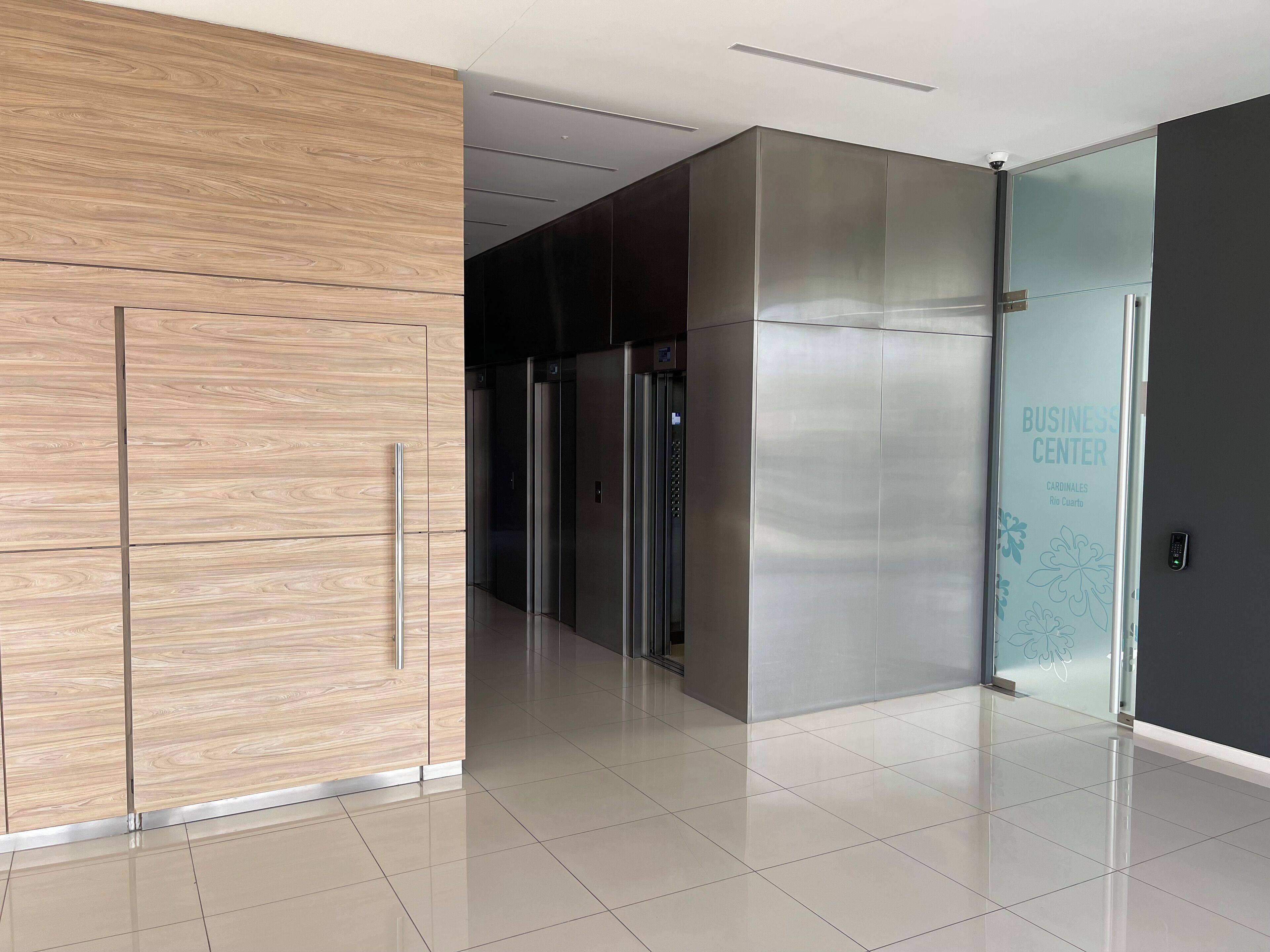 A modern elevator area with a metallic elevator and a glass elevator door labeled "BUSINESS CENTER".