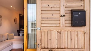 A wooden wall with a mail slot and a door, a sofa, and a glimpse of a dining area.