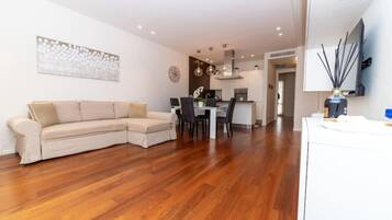 A modern living room with a sectional sofa, a dining area, and a kitchen in the background.