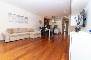 A modern living room with a sectional sofa, a dining area, and a kitchen in the background.