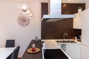 Une cuisine moderne équipée d’une cuisinière intégrée, d’un évier et d’une horloge murale.