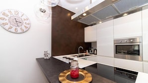 A modern kitchen with a central island, stainless steel appliances, and a decorative clock on the wall.