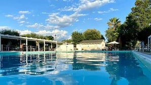 A clear blue sky with a few clouds, a swimming pool, and some trees in the background.