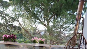 An outdoor patio with two wicker chairs, a cushioned swing chair, and a small table with a potted plant.