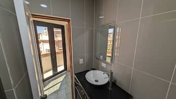 A modern bathroom with a large mirror, a sink, and a door leading to an outdoor area.