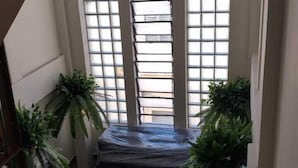 Een ruime kamer met grote ramen, een kroonluchter en potplanten.