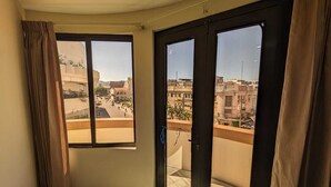 Een kamer met een groot raam en schuifdeuren, met uitzicht op een stadsbeeld.