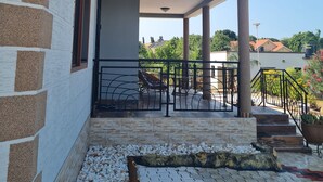 A two-story building with a balcony, outdoor seating, and a garden area.