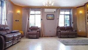 A living room with two leather sofas, a chandelier, and a large window with curtains.
