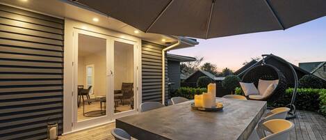 An outdoor patio with a dining table, chairs, and a large umbrella.