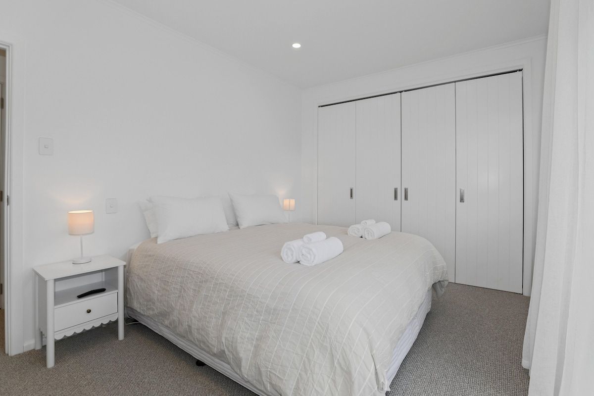 A bedroom with a bed, nightstand, and wardrobe.