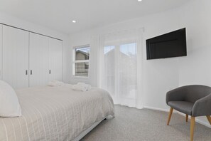 A bedroom with a bed, a chair, a TV, and a wardrobe.