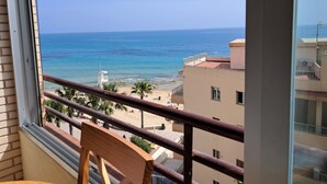 Ein Balkon mit Blick auf das Meer und den Strand, ein Rettungsturm und ein Gebäude mit der Aufschrift 'MARIA'.
