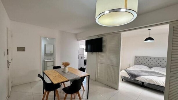 Una habitación compacta con comedor, cama y televisión.