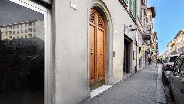 Una calle estrecha con un edificio que presenta un amplio ventanal y una puerta de madera.
