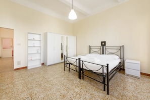 Une chambre à coucher comprenant un lit, une armoire, une table de chevet et un luminaire suspendu.